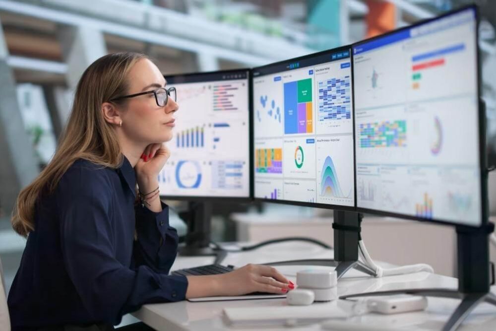 Woman reviewing content performance metrics on dual monitors