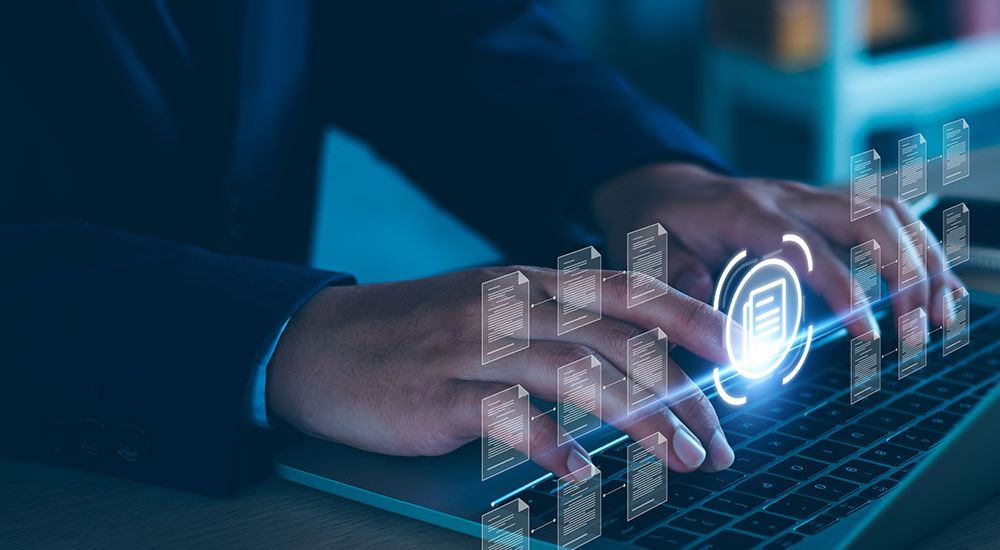 Hands typing on a laptop with digital document icons illuminating, symbolizing online data management and technology.