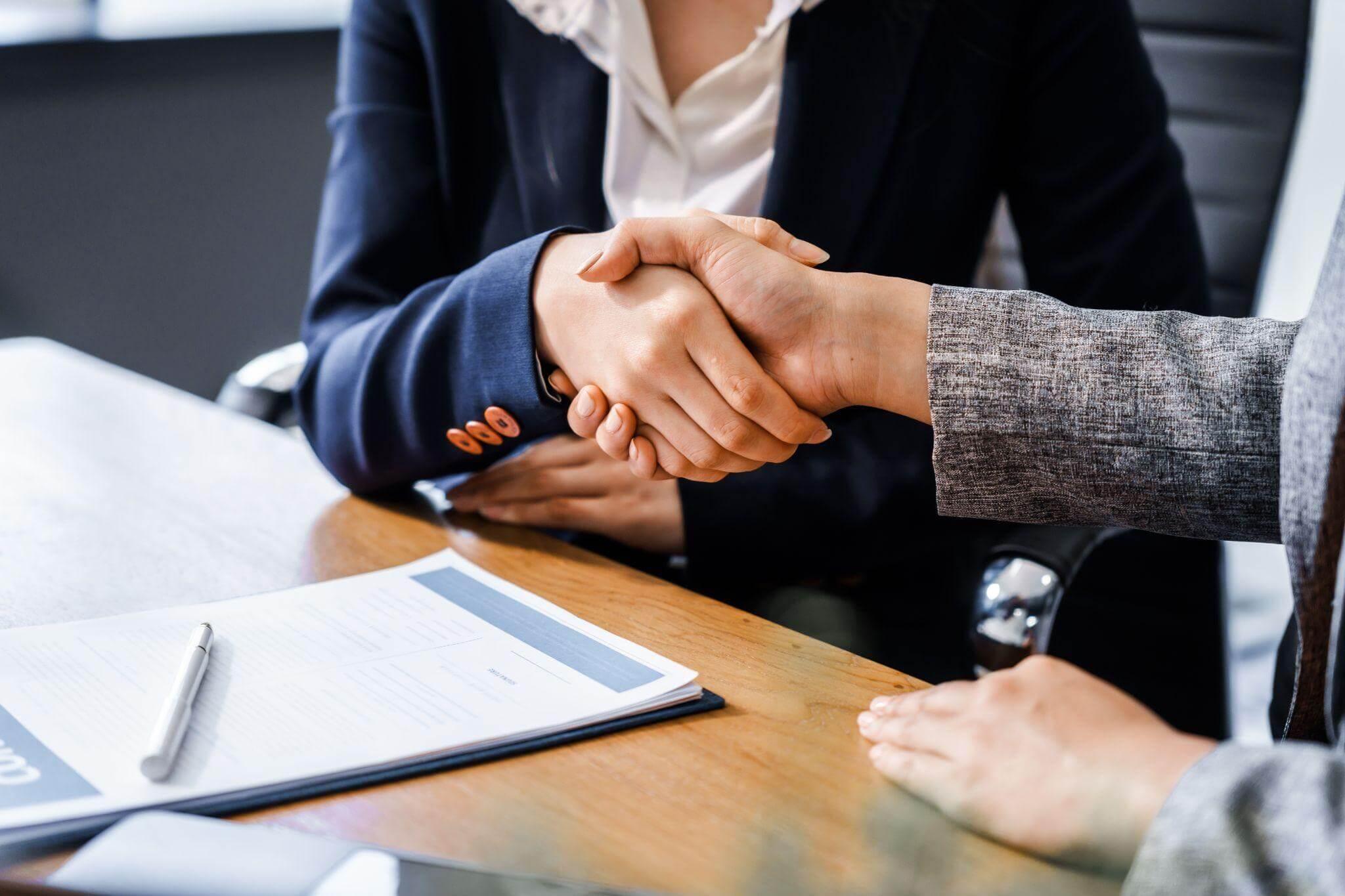 two people shaking hands over a wooden table